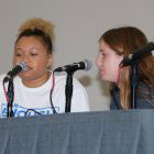 two teens at table in front of microphones