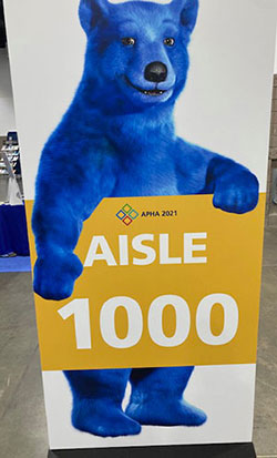 Blue Bear holding Aisle 1000 sign