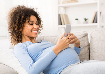 smiling pregnant woman look at phone