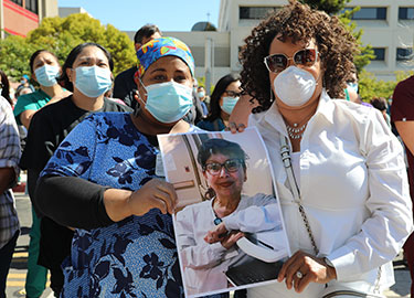 masked health workers holding photo of colleague
