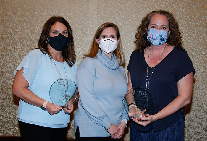 Two recipients of Council of Affiliates awards pose with a presenter. 