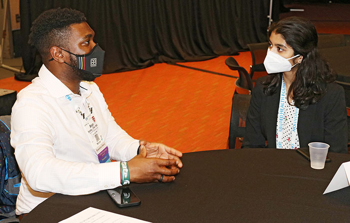 Two attendees sit at a table chatting. 