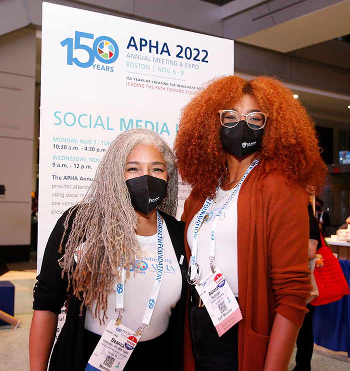 Two attendees wearing masks pose for the camera. 