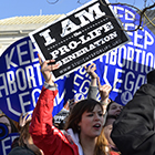 Women hold up abortion rights signs  at a protest.