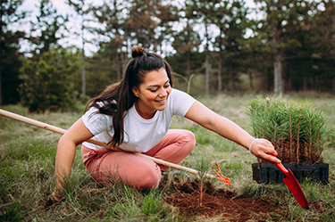 A woman smiles while working in a community garden