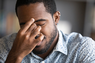 Man with hand held up to temple looking depressed