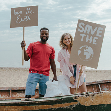 Two people hold signs advocating for saving the earth from human pollution