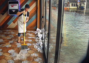 Worker sweeps flooding water in business