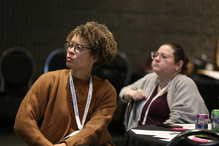 Two attendees at a table listen intently to the presenter at the APHA Learning Institute course on Reimagining Public Health Leadership for Health Equity