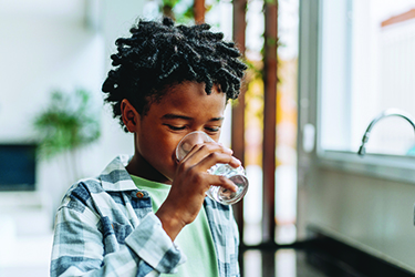 A boy drinks water from a glass
