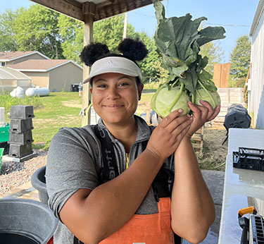 A worker holds up produce grown at a farm in Hugo, Minnesota, run by American Indians.