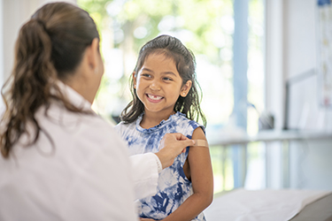 A child smiles after receiving a vaccination