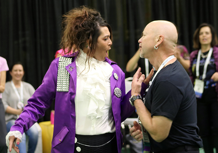 A person dressed up as the singer Prince dances with another person. 