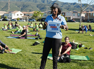 A woman holds a sign behind a bunch of people on yoga mats