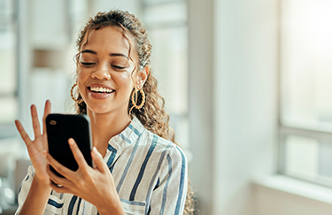 Woman smiles as she looks at her cell phone