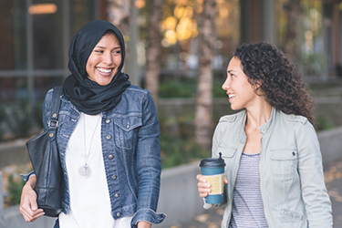 Two women walk along a street smiling