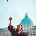 smiling woman throwing graduation cap in air