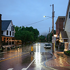 Person walks across Vermont street as rain falls
